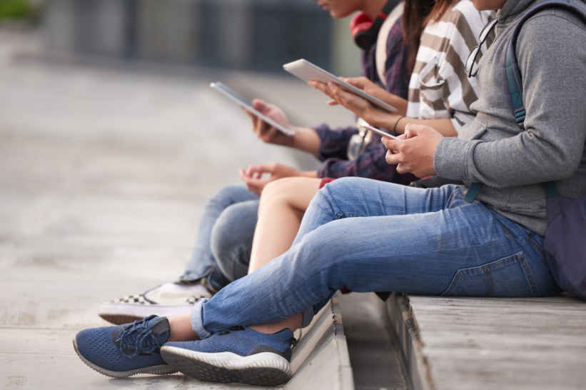 People using smartphones illustrating how online curiosity is triggered by mobile and social exposure.