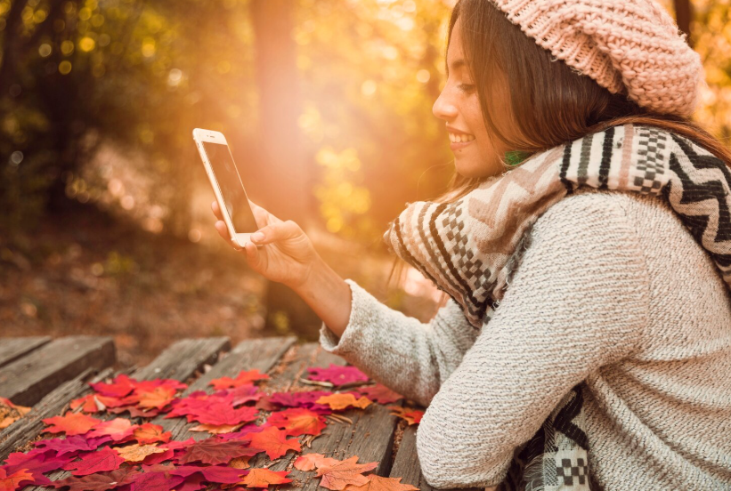 Person using a smartphone outdoors in autumn illustrating seasonal search behavior.