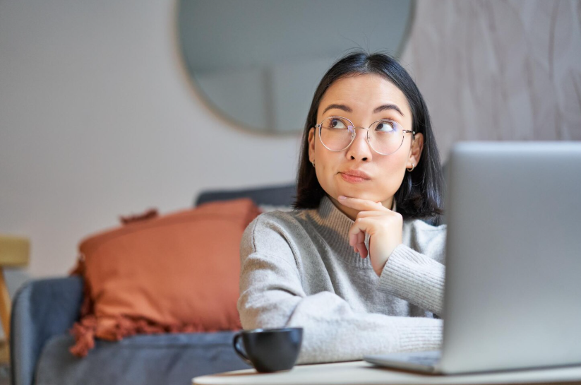 Woman thinking at a laptop illustrating what does this mean searches.